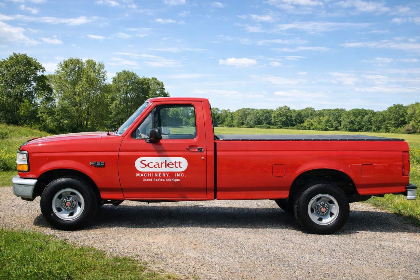 A red Scarlett Machinery Inc. pickup truck