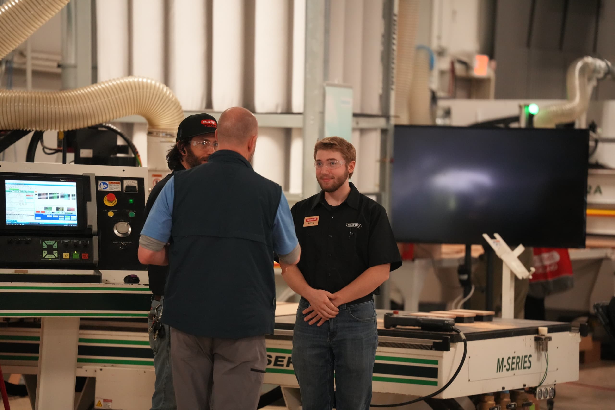 Scarlett team members talking on the shop floor beside a C.R. Onsrud M-Series CNC router